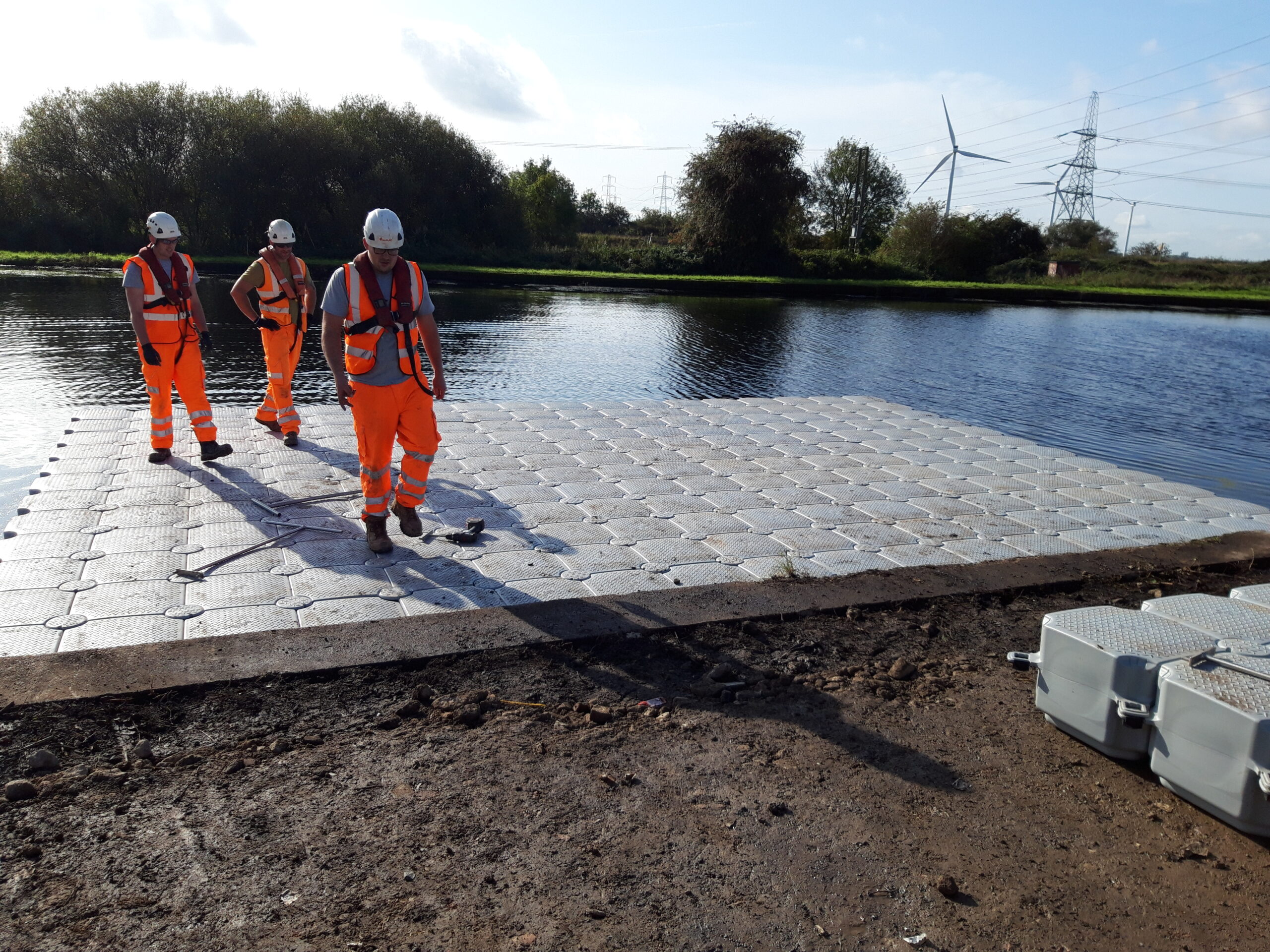 Workers in high-vis on floating platform by river